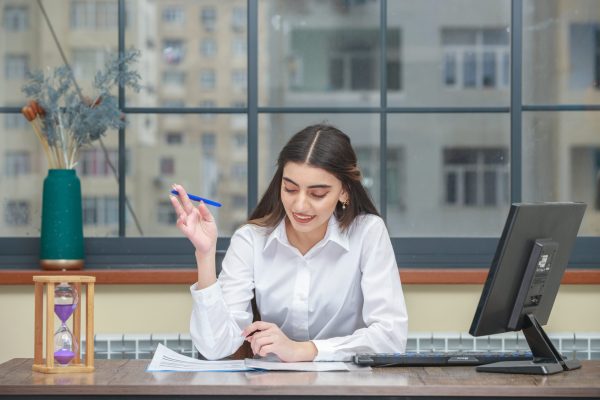 Portrait of a young businesswoman sitting at the desk and reading her notebook. High quality photo