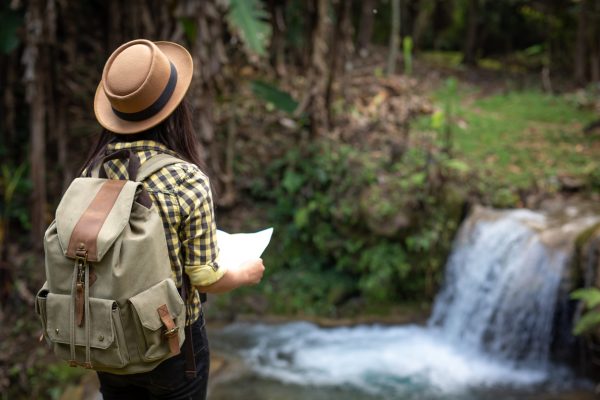 The lifted girl smiled happily in the hand with a backpack map.